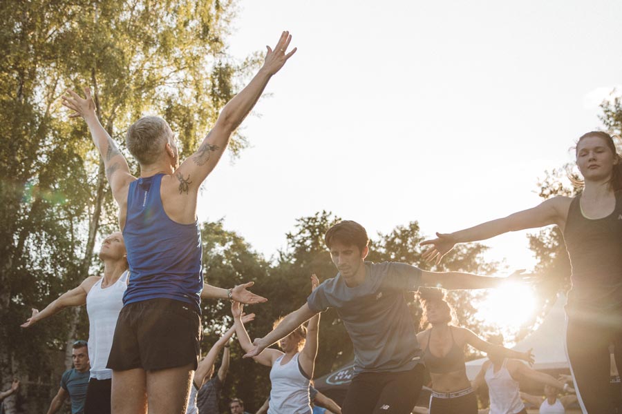 Joachim Koch mit Teilnehmer:innen eines Yogakurses für Unternehmen unter freiem Himmel.